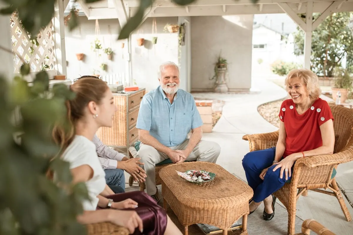 An adult child and an elderly parent talking together on a sofa at home.