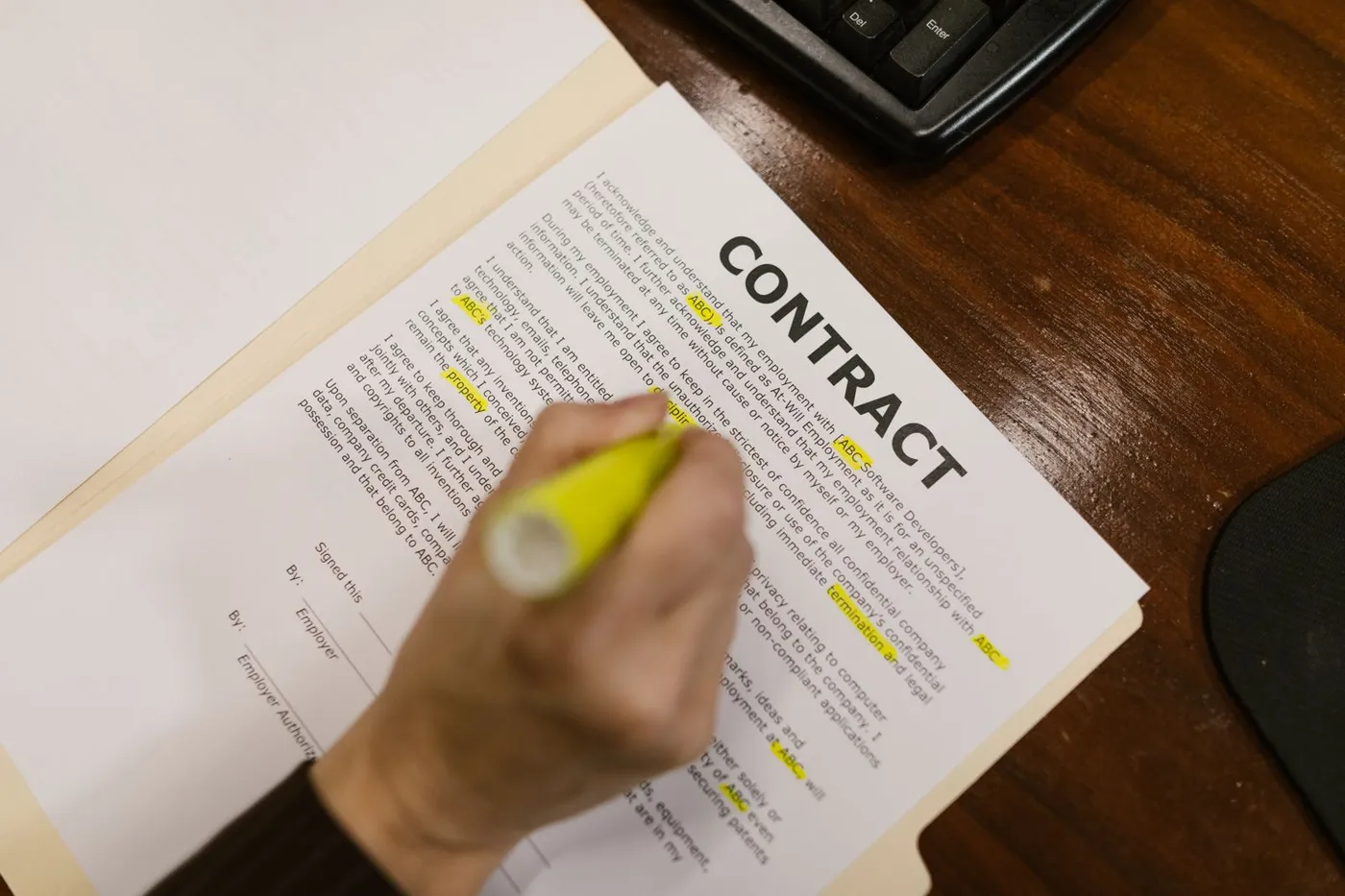 A person highlighting important text in a printed contract document.