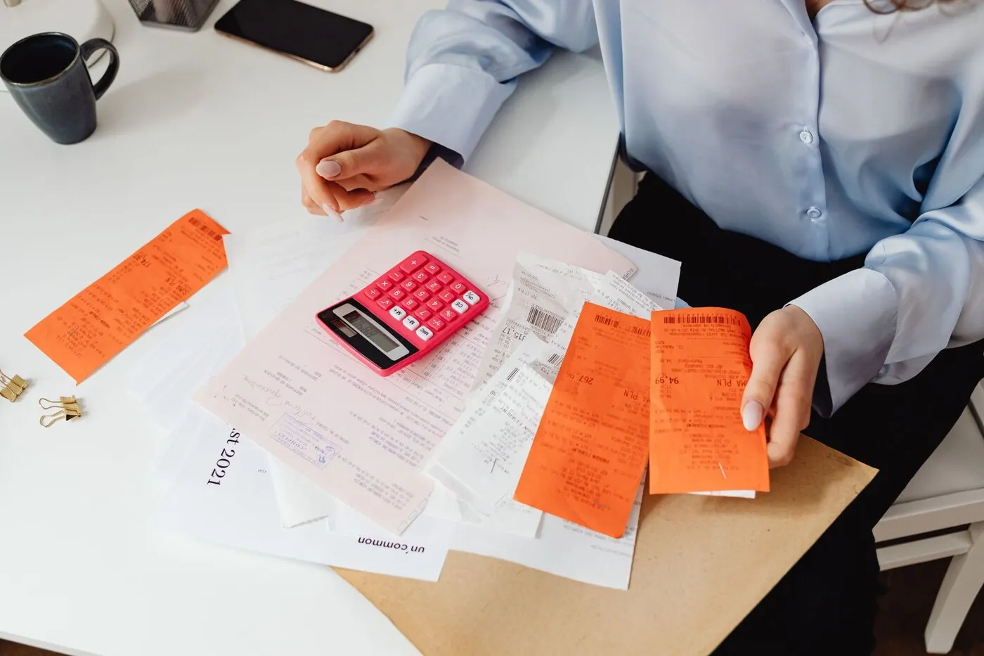 A calculator on a desk surrounded by receipts and printed statements.