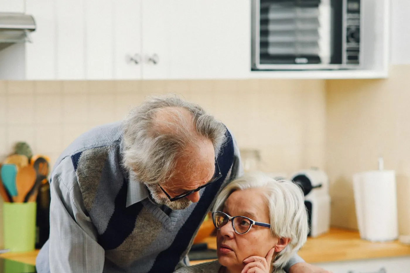 A senior couple reviewing paperwork together in a bright kitchen.