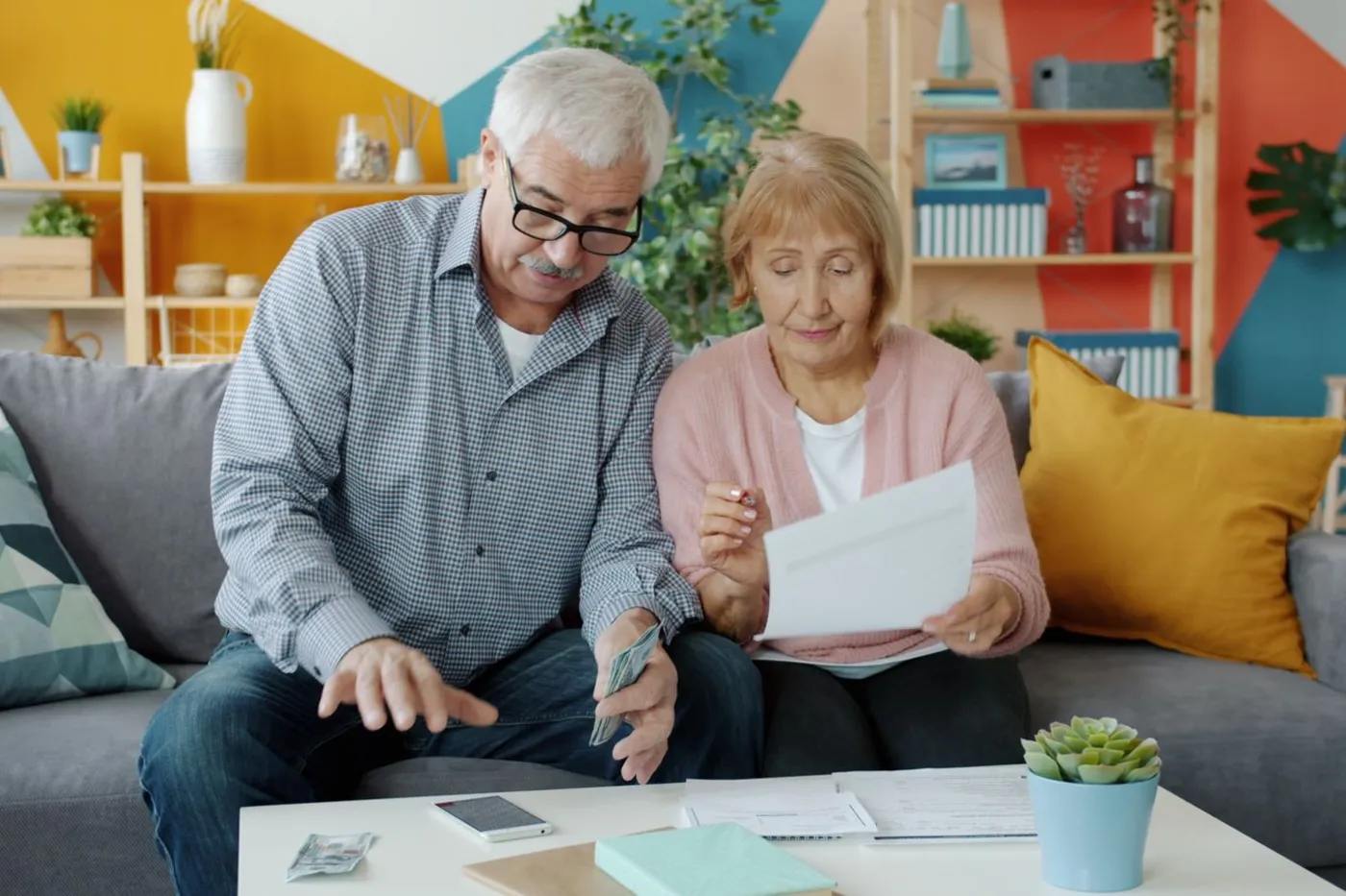A senior couple reviewing paperwork together in a cozy living room.