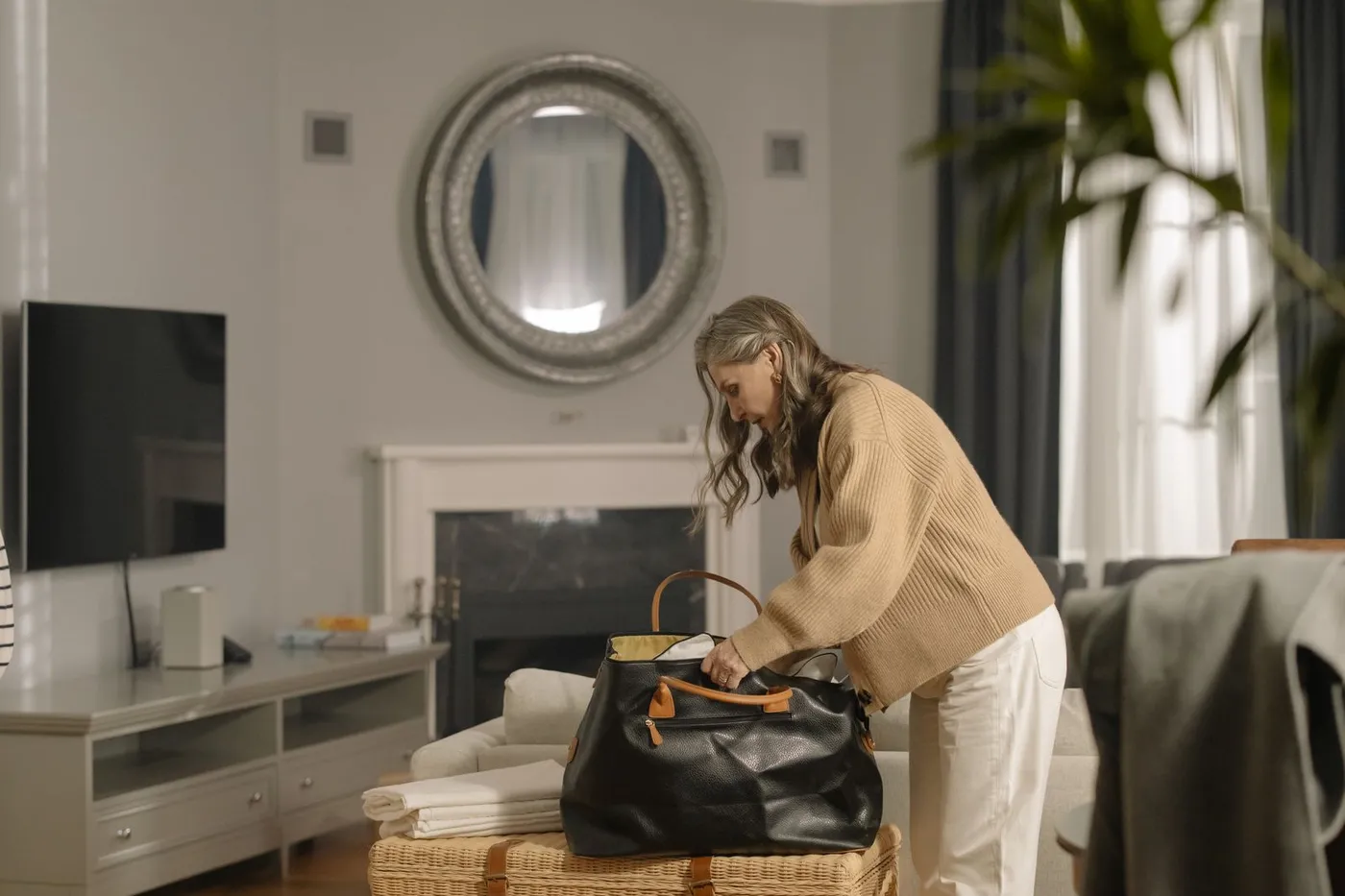 A senior woman packing a bag of belongings in her living room before a move.