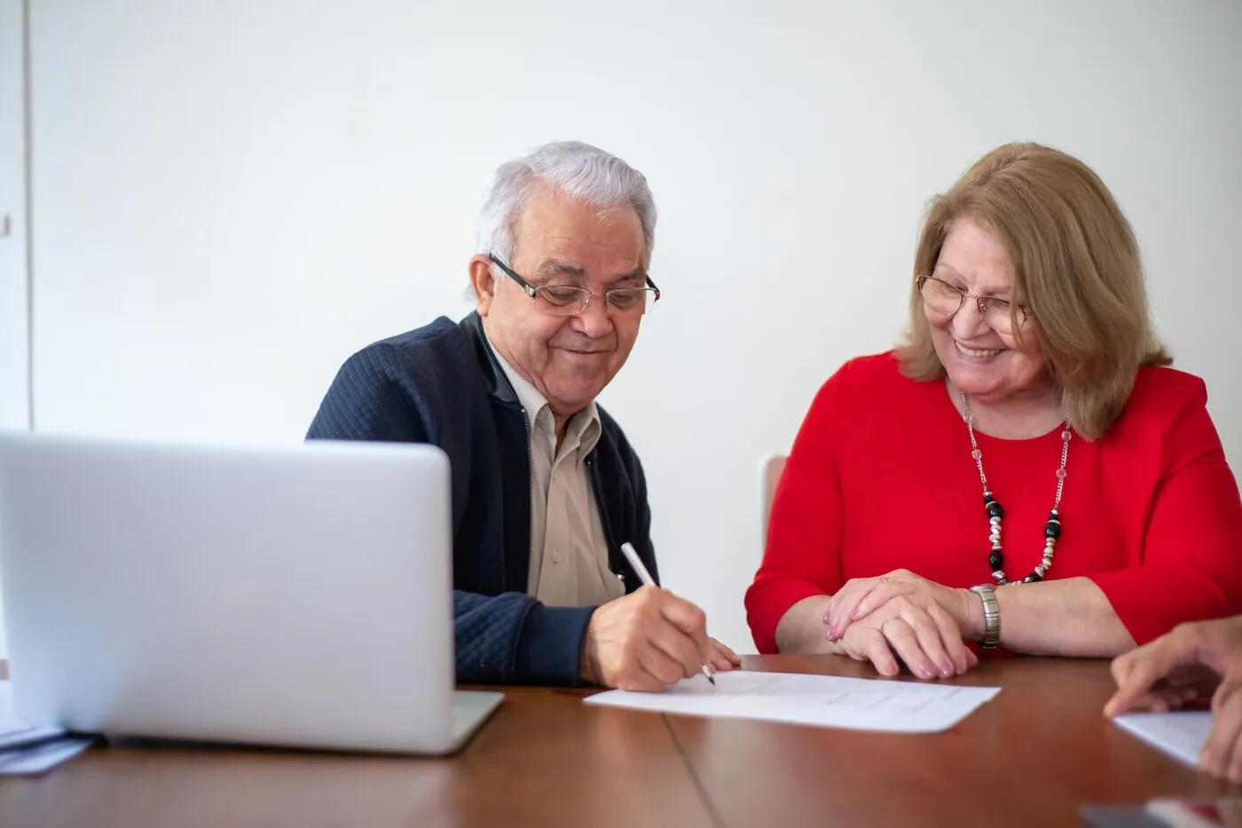 An active older couple reviewing paperwork together at a sunlit kitchen table.