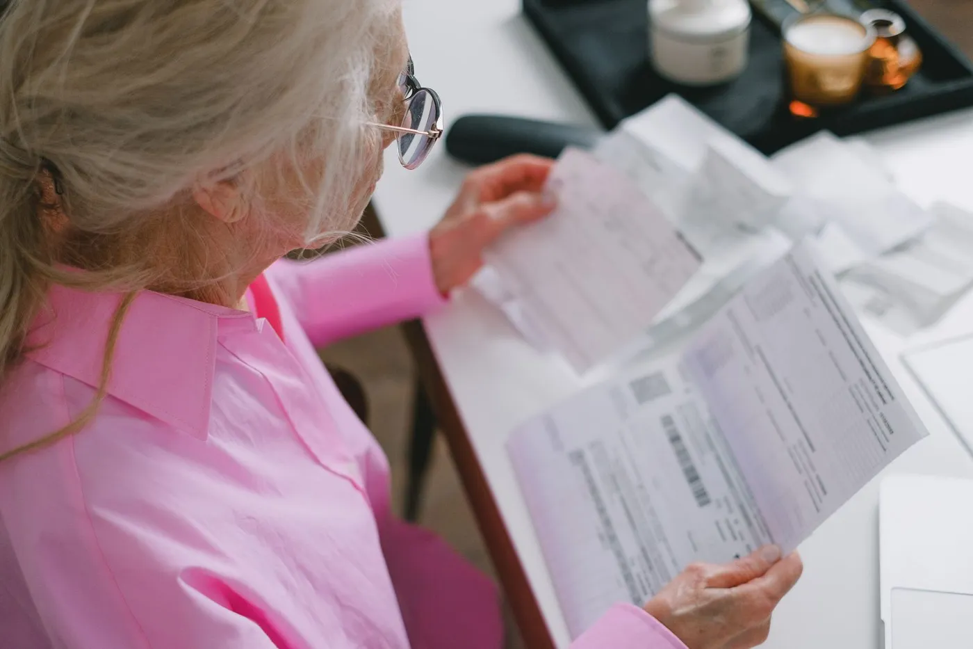 An older woman reading through insurance benefit paperwork at a table.
