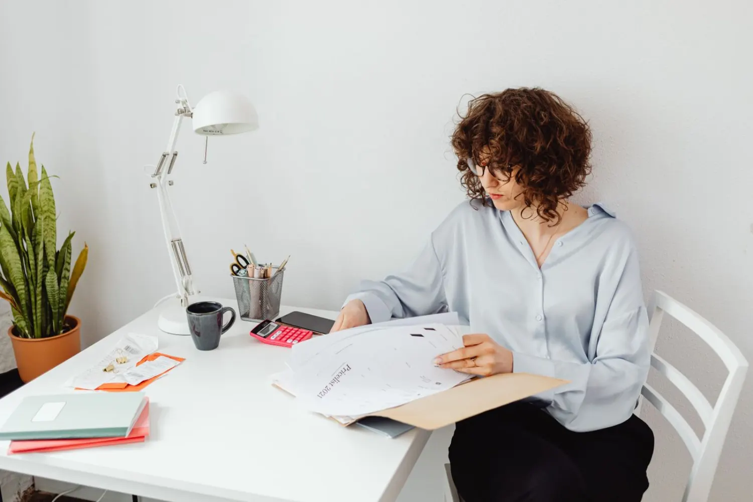 A person at a desk reviewing a price list with a calculator and receipts.