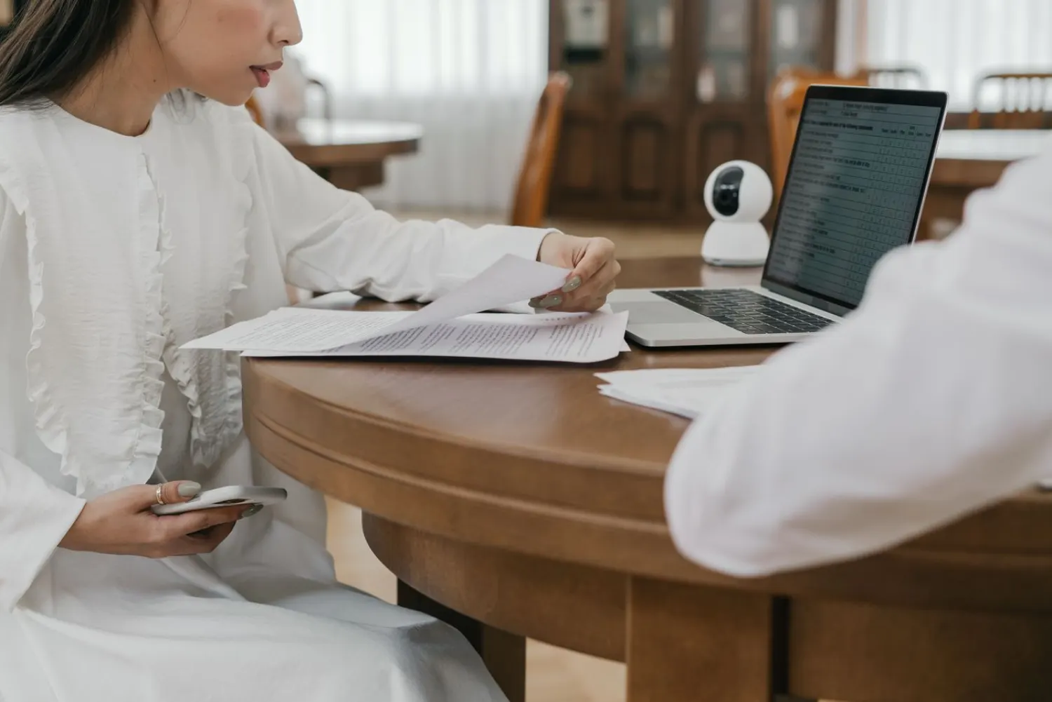Two people at a table reviewing printed documents with a laptop open beside them.